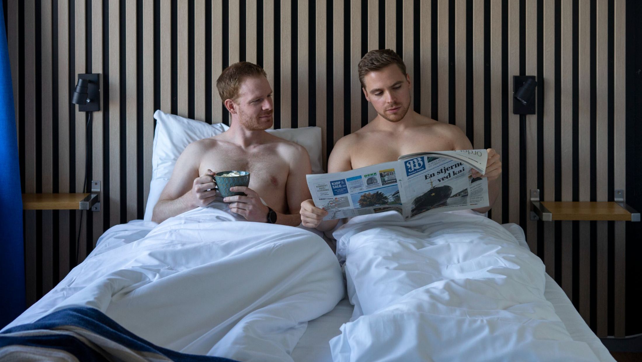To menn leser avis i sengen